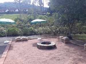 una hoguera y dos sombrillas en un patio en Pousada Verde Paraíso en Nova Petrópolis