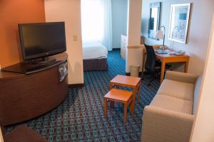 een hotelkamer met een televisie en een bank bij Fairfield Inn & Suites Oakland Hayward in Hayward