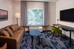 a living room with a couch and a desk and a television at Fairfield by Marriott Inn & Suites Pensacola Pine Forest in Pensacola