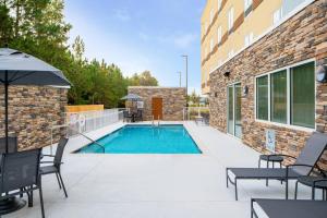 einen Pool auf einer Terrasse mit Stühlen und einem Sonnenschirm in der Unterkunft Fairfield by Marriott Inn & Suites Pensacola Pine Forest in Pensacola