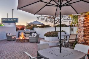 a patio with a table with an umbrella and a fire pit at SpringHill Suites Prescott in Prescott
