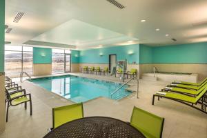 une grande piscine avec des chaises vertes et un billard dans l'établissement SpringHill Suites by Marriott Reno, à Reno