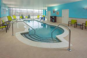 a swimming pool in a building with chairs and tables at SpringHill Suites By Marriott Frederick in Frederick