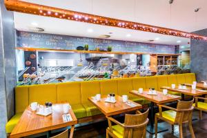 プルゼニにあるコートヤード バイ マリオット ピルセンの木製テーブルと黄色いソファのあるレストラン