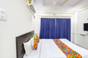 a bedroom with a white bed and a blue curtain at FabHotel Villa 31 in Nagpur