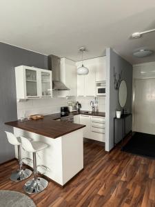 a kitchen with white cabinets and a wooden floor at Compact apartment in Rauma in Rauma
