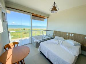 a bedroom with a bed and a table and a tub at ATLANTIC MARLIN HOTEL in Guriri