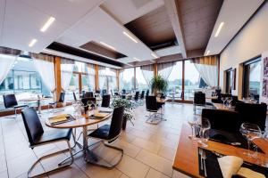 a restaurant with tables and chairs and large windows at Jura Sport & Spa Resort in Saignelégier