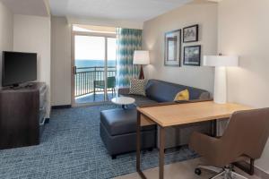 Habitación de hotel con escritorio, sofá y TV en Residence Inn By Marriott Virginia Beach Oceanfront, en Virginia Beach