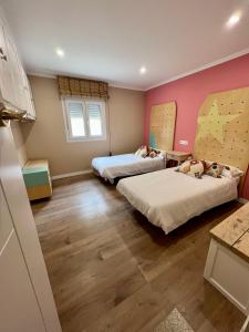 Habitación con 2 camas, paredes de color rosa y suelo de madera. en La casita de Ouriceira, en Combarro