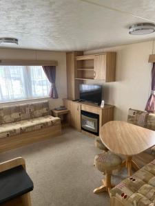 a living room with a table and a living room with a couch at Golden Palm Resort PG163 in Chapel Saint Leonards