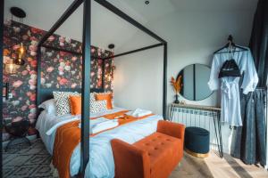 - une chambre avec un lit à baldaquin et une chaise orange dans l'établissement Priory Bay Escapes - Visum, à Tenby