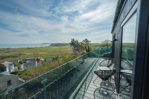 a balcony with two chairs and a view of the ocean at Priory Bay Escapes - Visum in Tenby