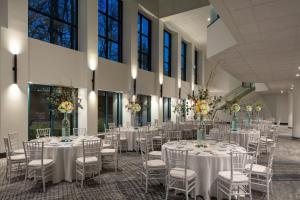 un salón de banquetes con mesas blancas, sillas y flores en Falls Church Marriott Fairview Park, en Falls Church