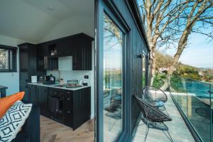 a kitchen with black cabinets and a large glass window at Priory Bay Escapes - Visum in Tenby