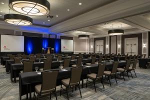 a conference room with tables and chairs and a screen at Falls Church Marriott Fairview Park in Falls Church