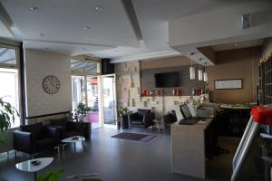 a lobby with couches and tables and a clock on the wall at Hotel Hercegovina in Mostar