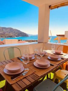 una mesa de madera con platos y copas de vino. en Balcón al mediterráneo en Almuñécar