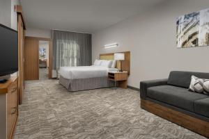 SpringHill Suites by Marriott Tuscaloosa في توسكالوسا: غرفه فندقيه بسرير واريكه