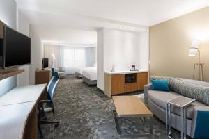a hotel room with a couch and a bed at Courtyard by Marriott Houston Katy Mills in Katy