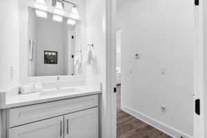 a white bathroom with a sink and a mirror at 30A Beach House - Mira Bella in Rosemary Beach +33 photos