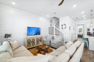 a white living room with a couch and a tv at 30A Beach House - Mira Bella in Rosemary Beach