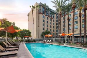 a pool with chairs and umbrellas in front of a hotel at Residence Inn Irvine John Wayne Airport Orange County in Irvine