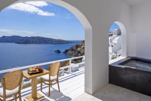 balkon ze stołem i krzesłami oraz widokiem na wodę w obiekcie White Pearl Villas w mieście Oia
