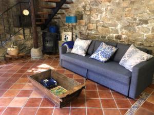 - un salon avec un canapé et un mur en pierre dans l'établissement Genciana, Casa Rural con encanto en La Montaña Leonesa, 