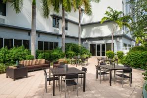 une cour avec des tables, des chaises et des palmiers dans l'établissement SpringHill Suites Miami Downtown/Medical Center, à Miami