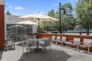 eine Terrasse mit Tischen, Stühlen und Sonnenschirmen in der Unterkunft SpringHill Suites by Marriott Sacramento Natomas in Sacramento