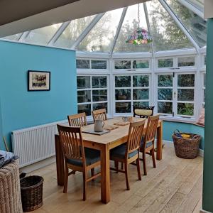 a conservatory with a table and chairs and a glass ceiling at April cottage in Winchelsea