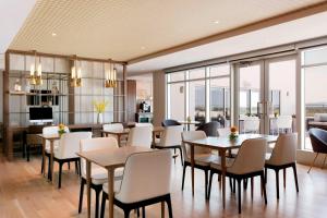 un comedor con mesas, sillas y ventanas en Sheraton Saint-Hyacinthe Hotel, en Saint-Hyacinthe