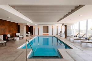 a pool in a hotel lobby with chairs and tables at Sheraton Saint-Hyacinthe Hotel in Saint-Hyacinthe