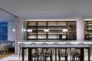 فندق شيراتون ملبورن في ملبورن: غرفة طعام مع طاولة وكراسي ورفوف للنبيذ