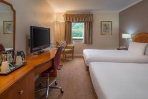 a hotel room with a bed and a desk with a television at Delta Hotels by Marriott Milton Keynes in Milton Keynes