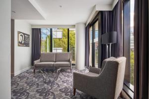 a living room with chairs and a couch and windows at Sheraton Melbourne Hotel in Melbourne