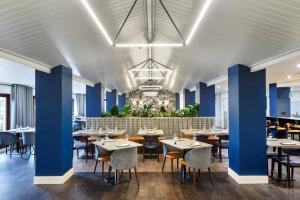 a restaurant with blue walls and tables and chairs at Delta Hotels by Marriott Milton Keynes in Milton Keynes