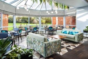 a conservatory with couches and tables and chairs at Delta Hotels by Marriott Milton Keynes in Milton Keynes