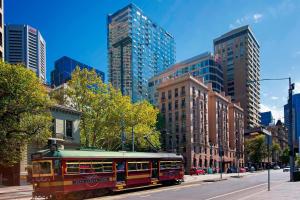 a trolley car on a city street with tall buildings at Sheraton Melbourne Hotel in Melbourne