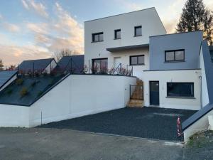 una casa bianca con un balcone sopra di Villa piscine/spa privé intérieur 33° ZOO DE LA FLECHE 24h DU MANS a La Flèche