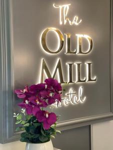 a vase with purple flowers in front of a sign at Old Mill Hotel & Lodge in Bath