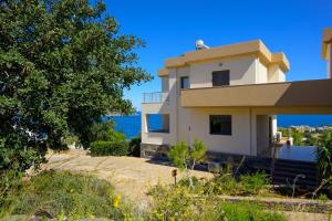 ein Haus am Strand mit einem Baum in der Unterkunft Elounda Blue Waves Residence in Elounda