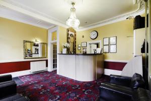 a living room filled with furniture and a clock on the wall at Tudor Court Hotel in London