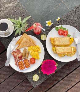 two plates of breakfast food on a table at Island Retreat Cottage in Nusa Lembongan