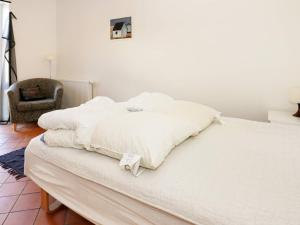 białe łóżko w pokoju z krzesłem w obiekcie Holiday home Storvorde XXII w mieście Storvorde