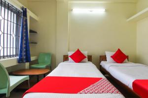 Cette chambre comprend 2 lits avec des oreillers rouges. dans l'établissement OYO Royal Residency, à Sūramangalam