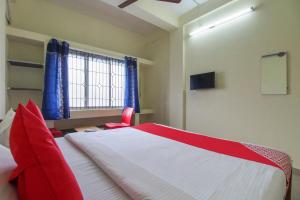 Schlafzimmer mit einem roten und weißen Bett und einem Stuhl in der Unterkunft OYO Royal Residency in Sūramangalam