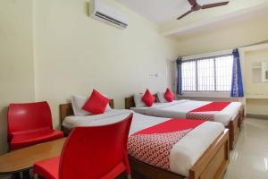 a room with two beds and a chair and a table at OYO Royal Residency in Sūramangalam