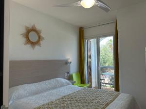 een slaapkamer met een bed, een plafondventilator en een spiegel bij Hotel & Appartements Punta e Mare in Cargèse